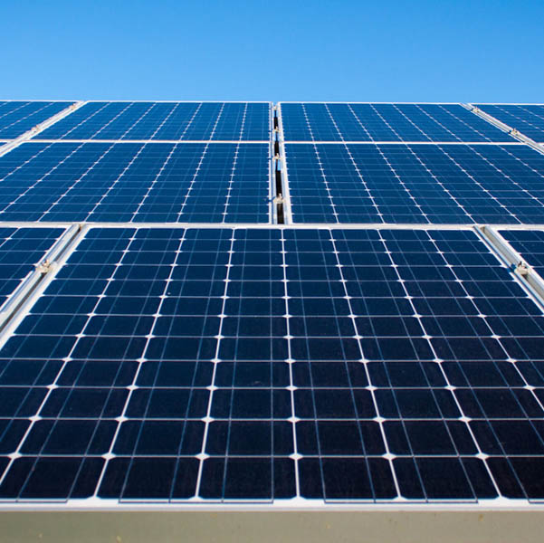Painéis solares fotovoltaicos sob céu azul representando geração de energia limpa e sustentável