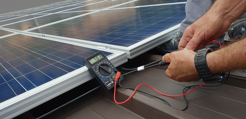 Profissional utilizando multímetro digital para medir tensão em sistema de painéis solares fotovoltaicos